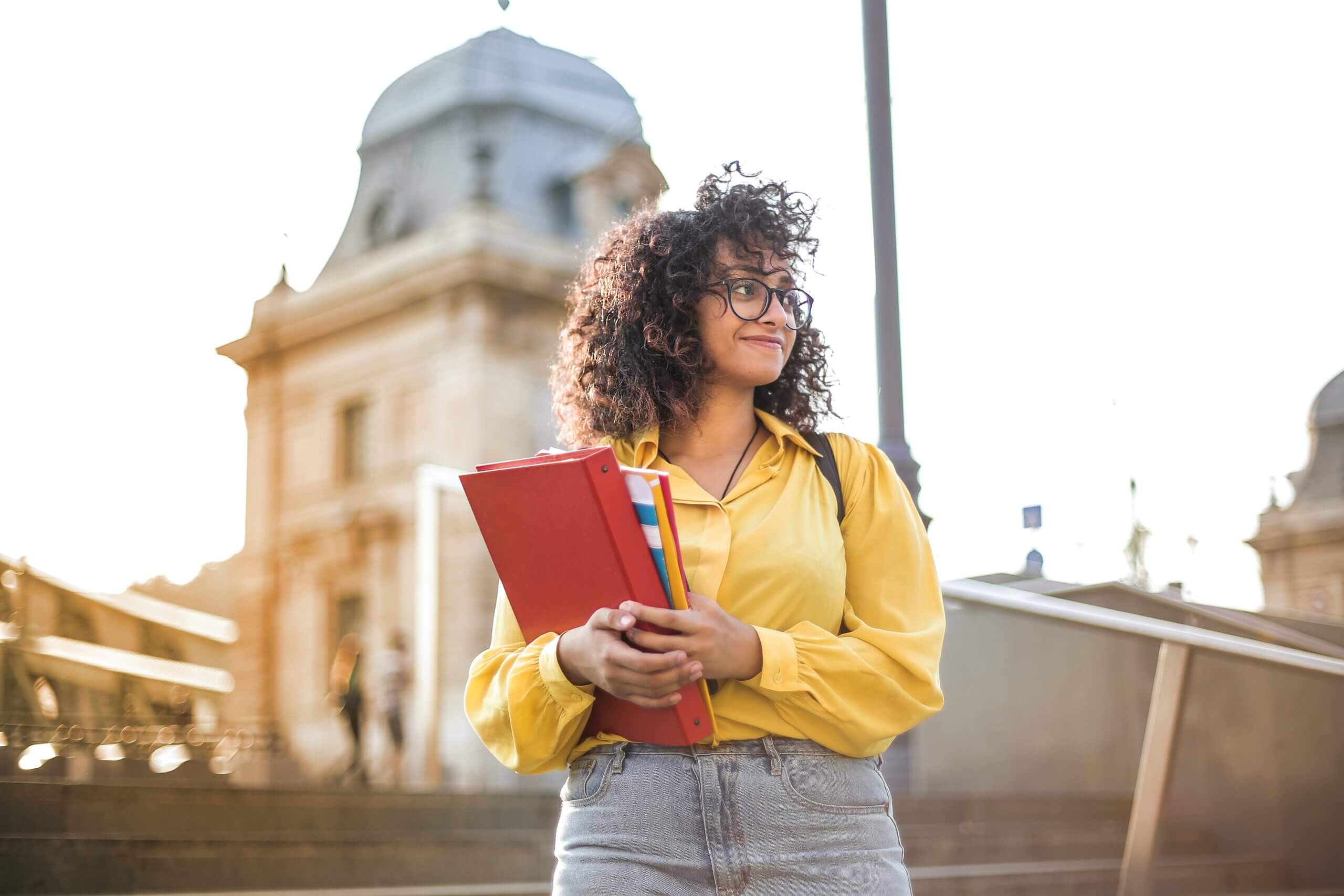 woman in yellow jacket holding red book 3762800 scaled