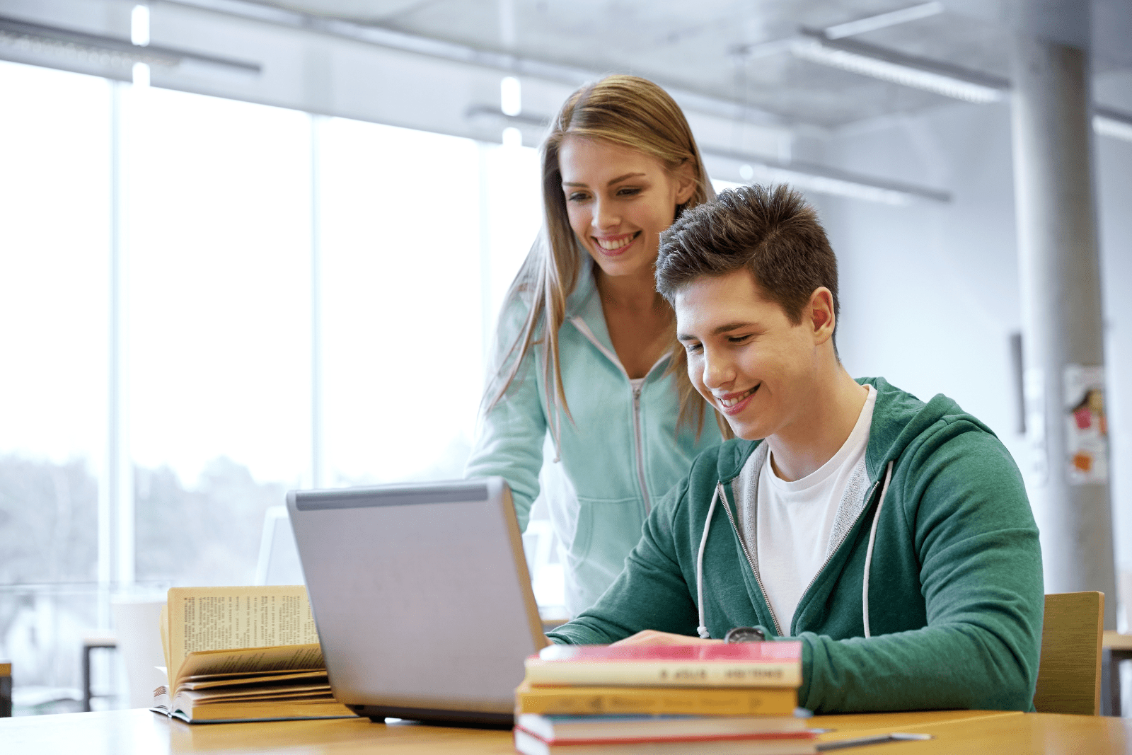 Student attending online grinds with a teacher providing guidance over his shoulder